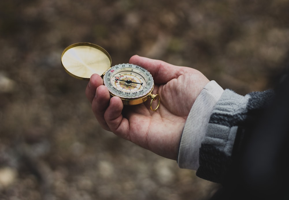 person using white and gold compass