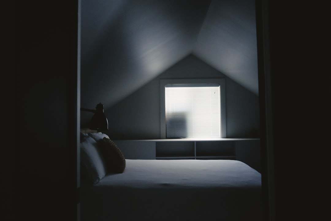 white bed frame beside attic window