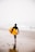 man holding yellow surfboard while walking on seashore during daytime