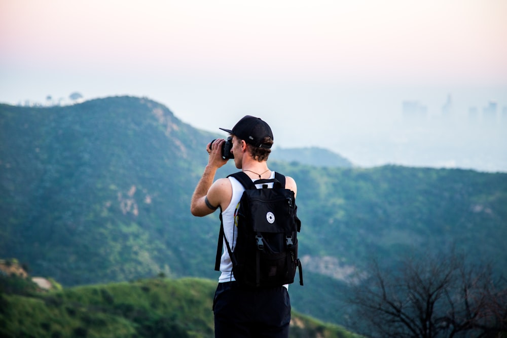 man wearing black backpack using telescope