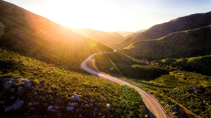 A winding road though a mountain with the sun setting