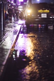 A nighttime shot of a Cruzz taxi driving through Doncaster streets with reflections on wet pavement