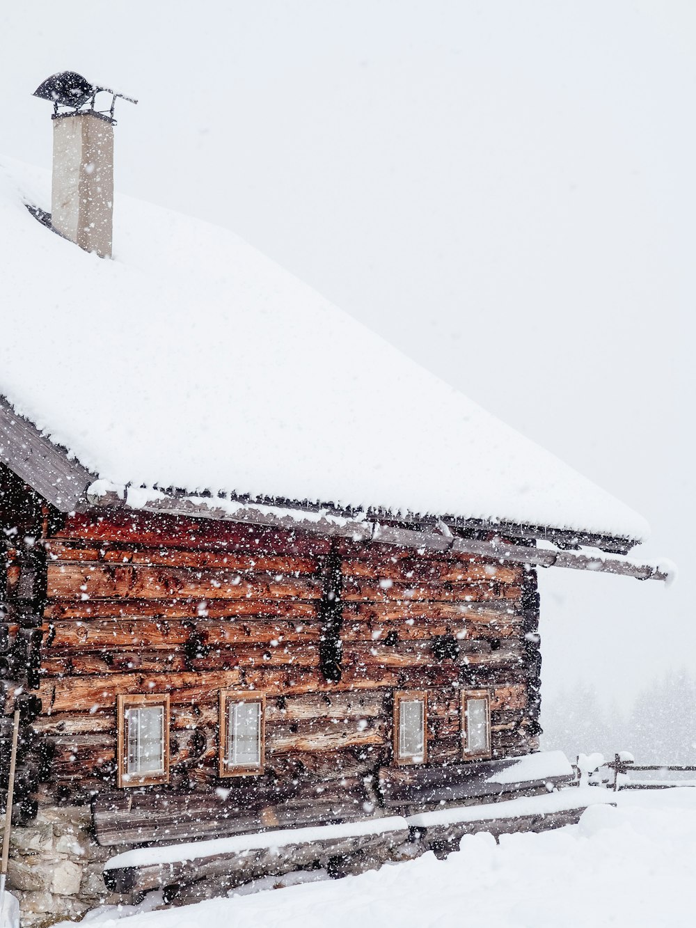 Casa de madeira marrom cheia de neve durante a neve