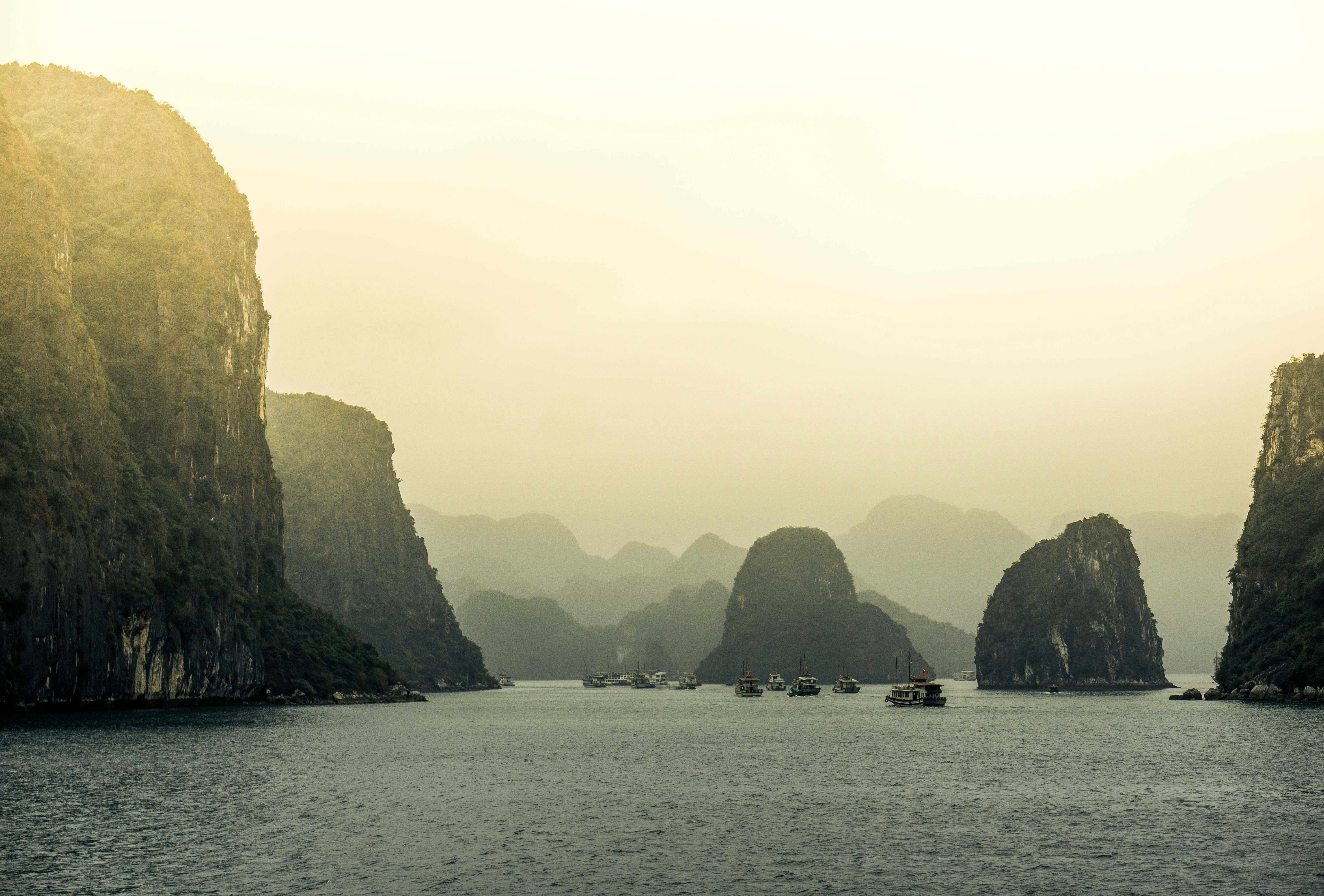boat surrounder by islands, We travel forwards on a foggy day into the shrouded mystery that is Ha Long Bay.