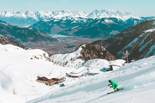 person riding on skis during winter surrounded by mountains in Kaprun Austria