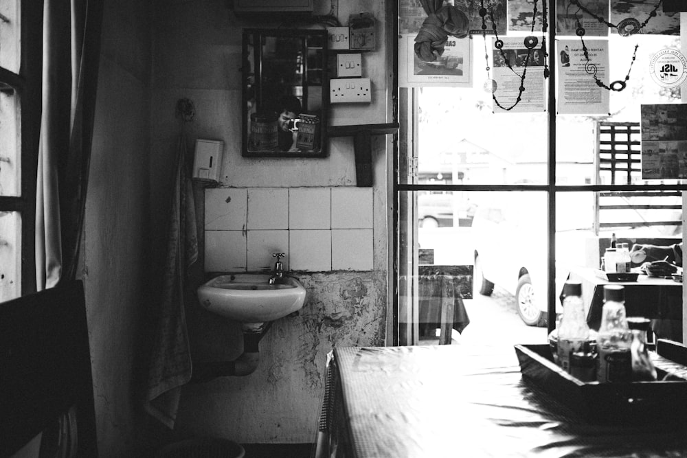 grayscale photo of woman in white dress standing near sink