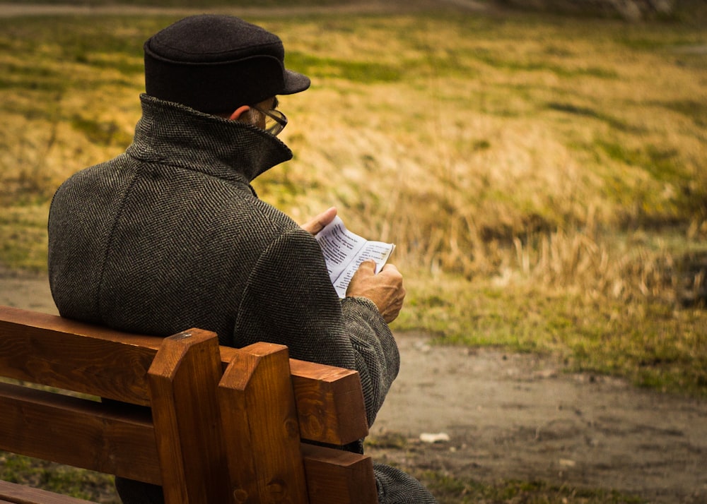 man holding paper sitting on bench