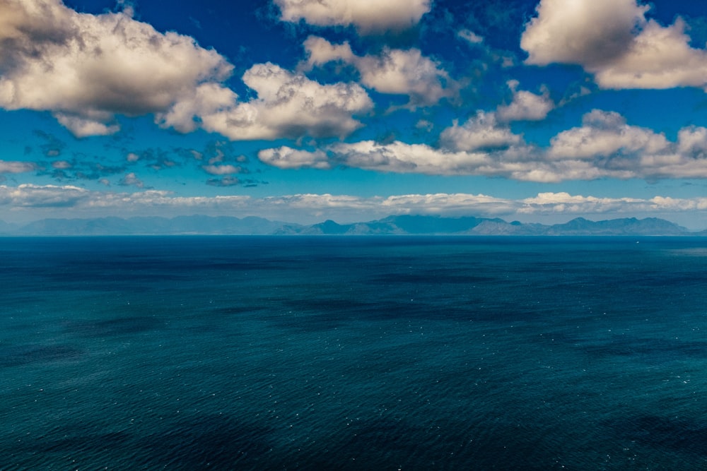 a large body of water under a cloudy blue sky