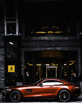 red coupe parked in front of black and gray building during daytime