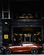 red coupe parked in front of black and gray building during daytime