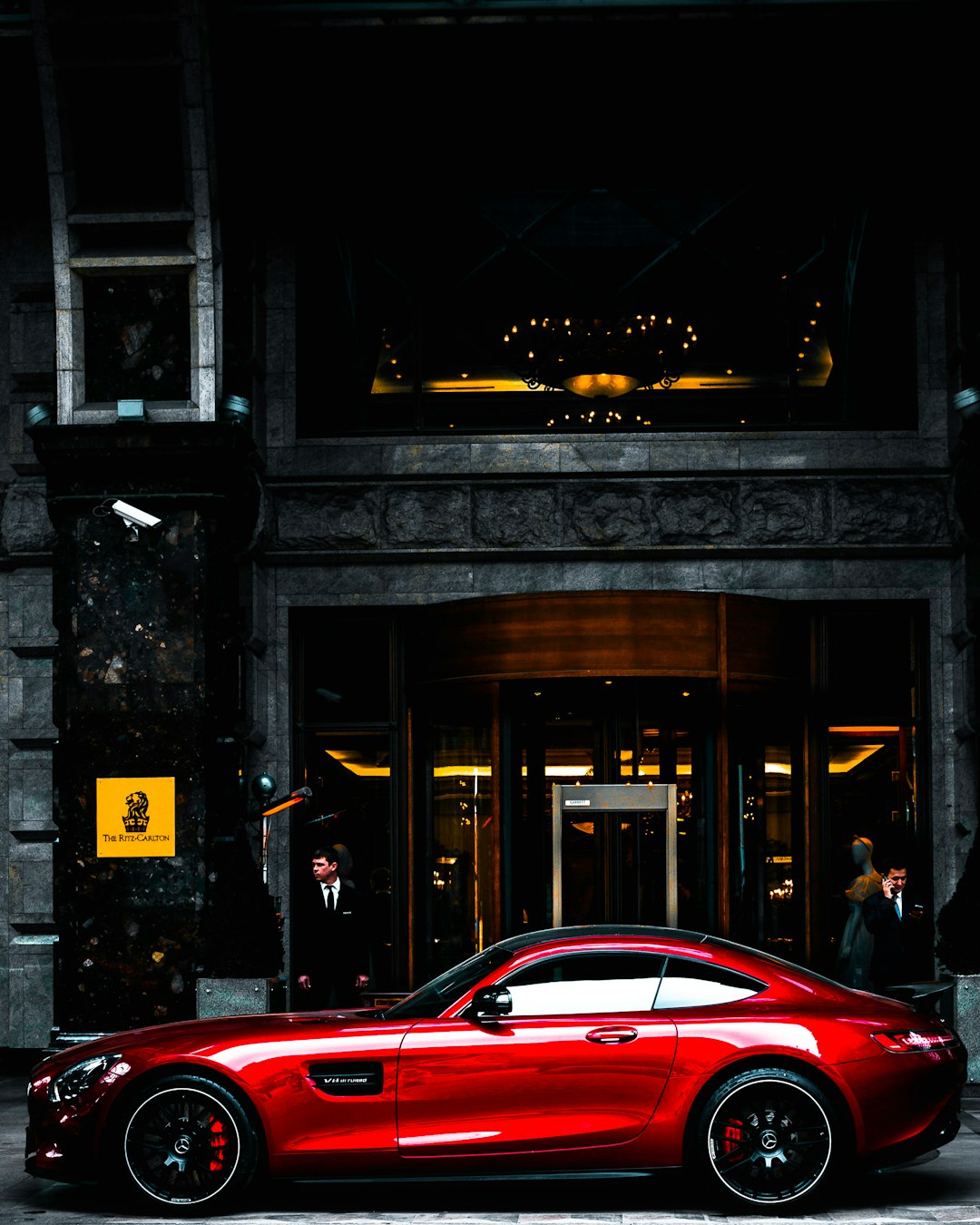 red coupe parked in front of black and gray building during daytime