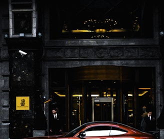 red coupe parked in front of black and gray building during daytime