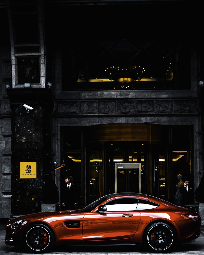 Red executive car parked near modern offices