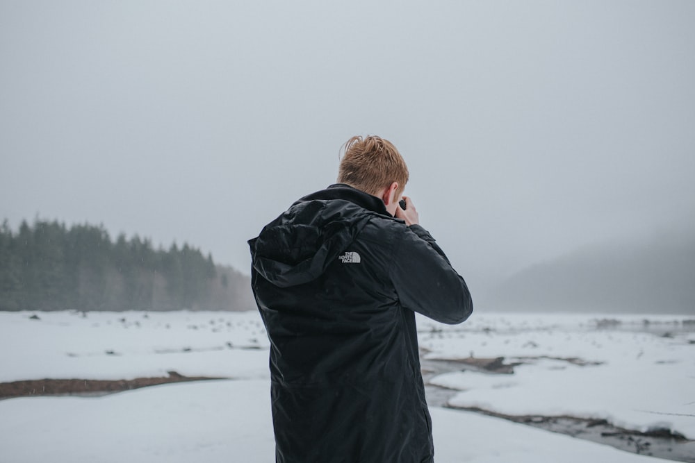 man taking picture under cloudy sky