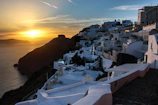 Sunset over the whitewashed buildings of Santorini with the Aegean Sea glowing in soft gold.