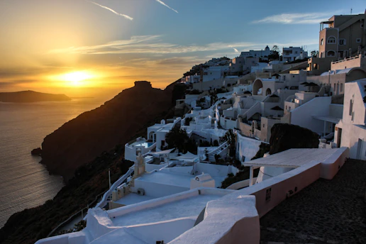 A breathtaking aerial view of Mijas coastline at sunset, with golden light reflecting on the sea and white village rooftops nestled among olive groves.