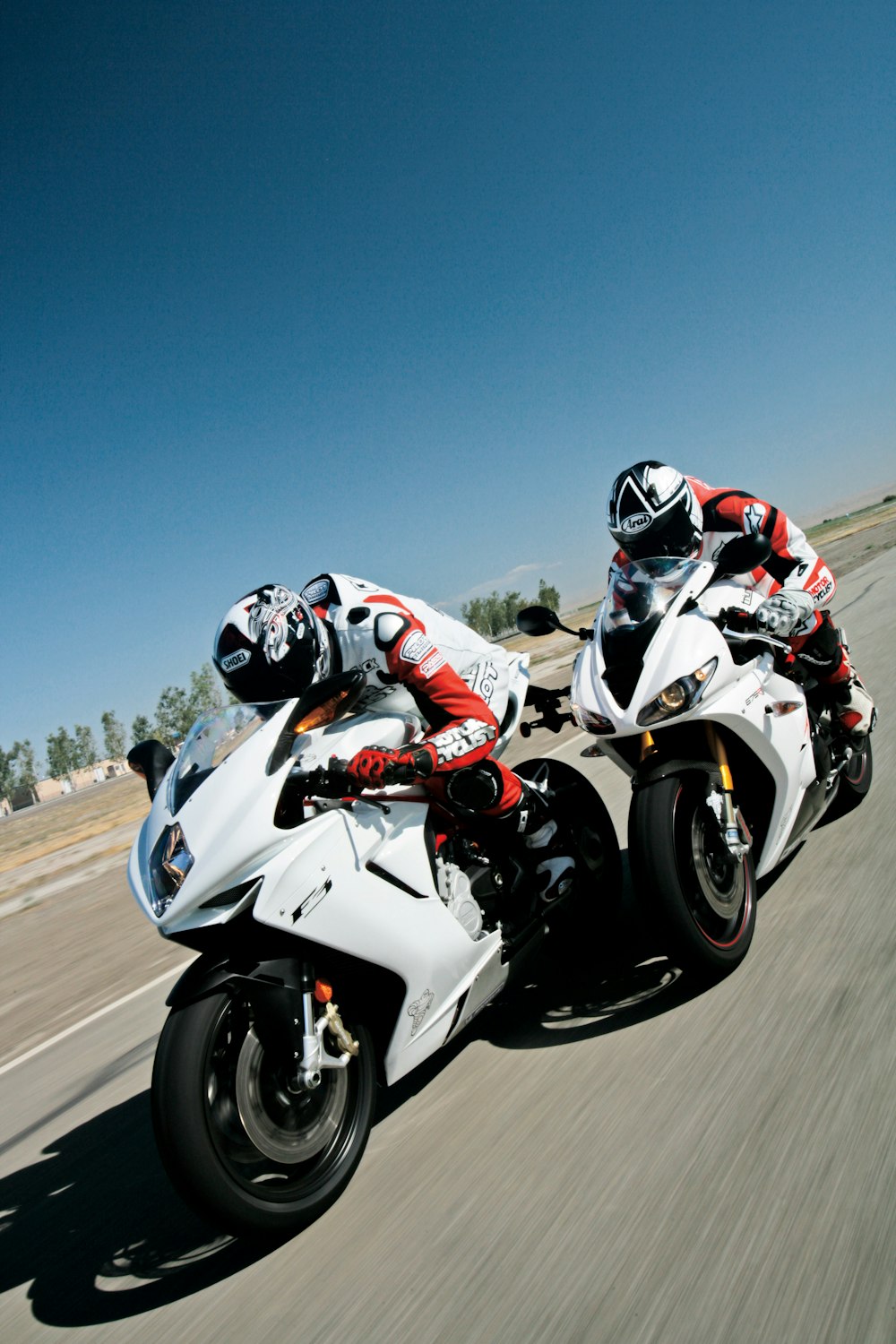 Deux personnes conduisant des motos de sport sur une route asphaltée grise pendant la journée
