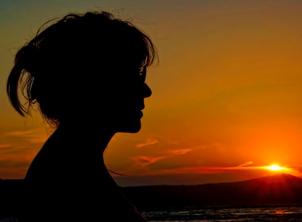 a woman is silhouetted against a sunset on the beach