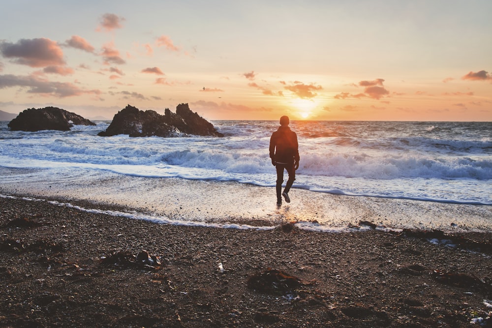 man walking in beach during golden hour