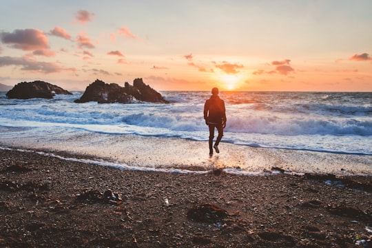 man walking in beach during golden hour in Wales United Kingdom