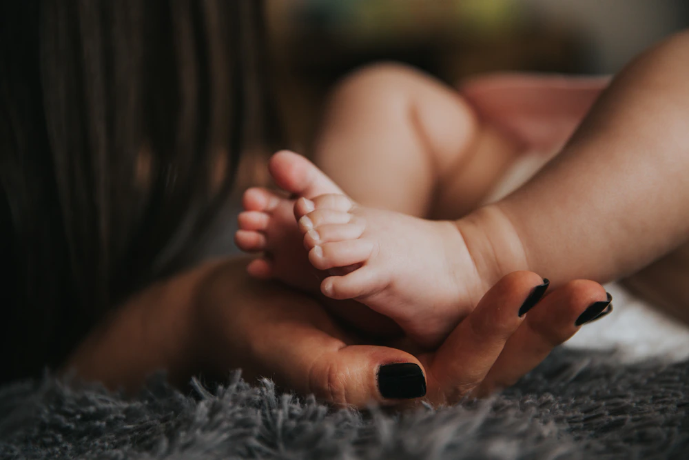 Tangan orang tua menggenggam lembut kaki bayi