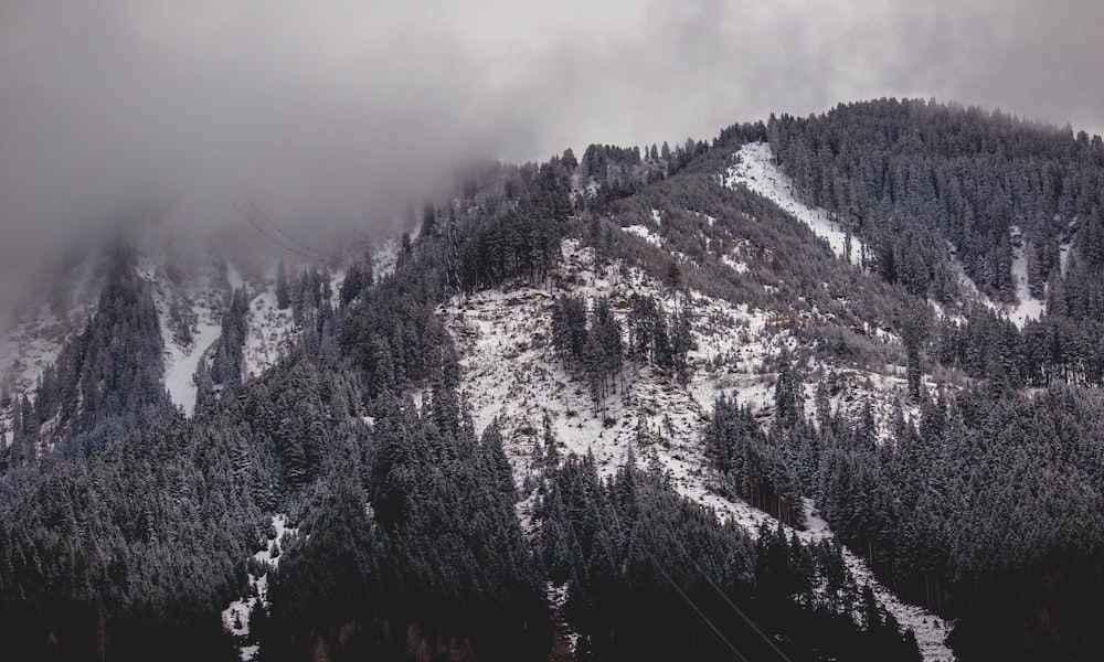 grayscale photography of snowy mountain covered by clouds