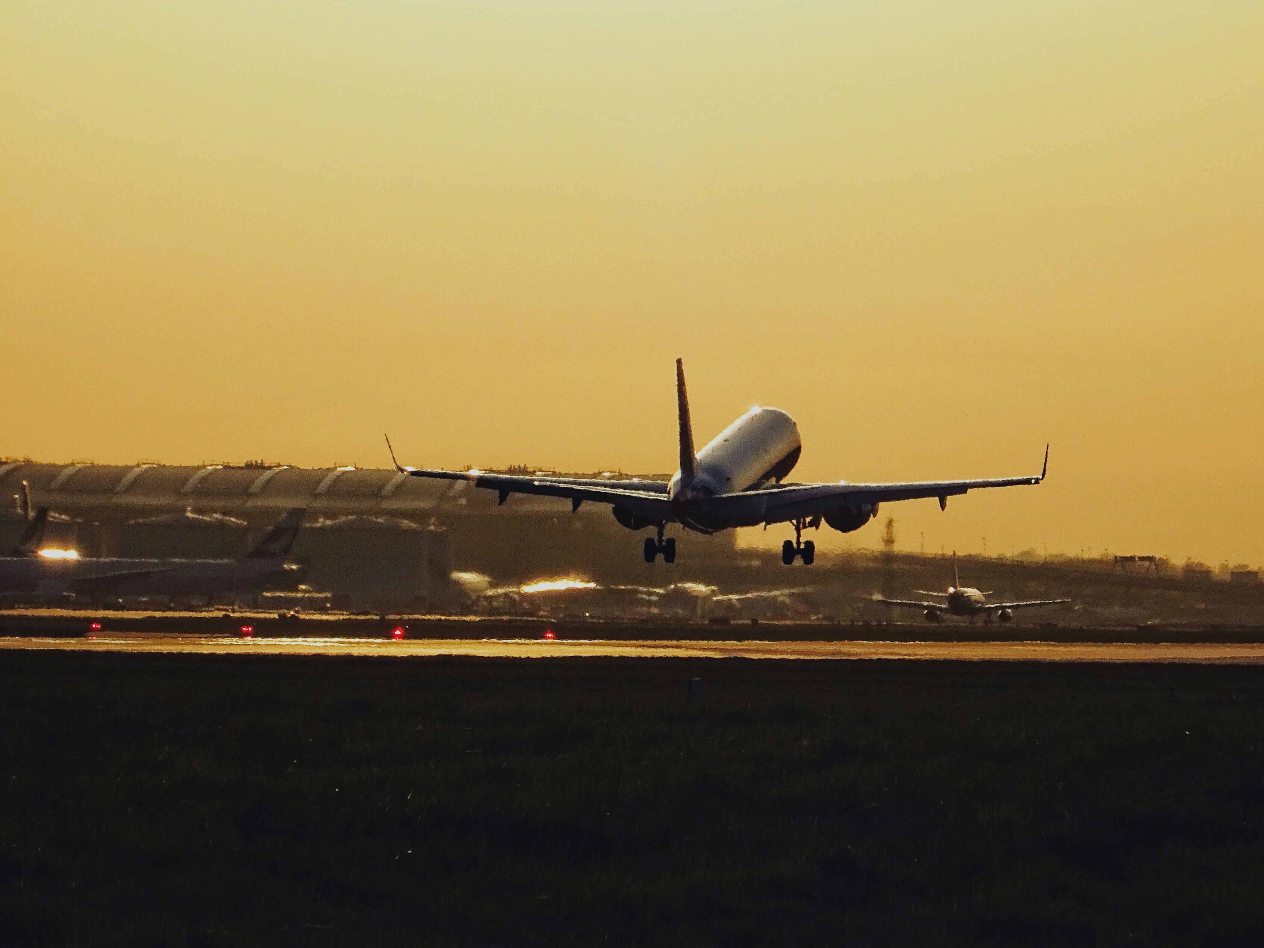 A cargo plane taking off from a busy international airport at sunset.
