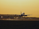 A modern cargo airplane taking off from an airport runway at sunrise.