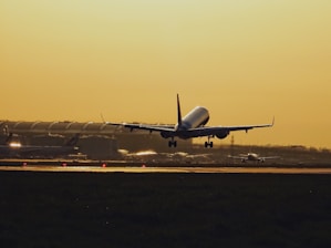 A cargo airplane taking off from an airport runway at sunset.