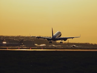 A sleek airplane taking off from a London airport at sunset.