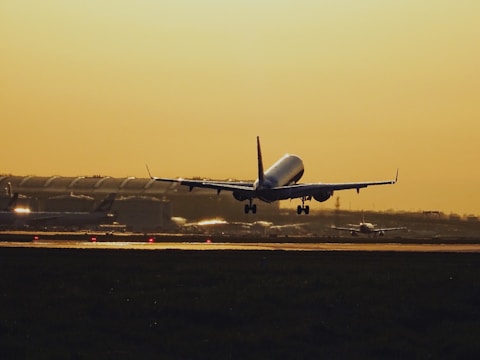 Airplane taking off from an airport runway during sunset.