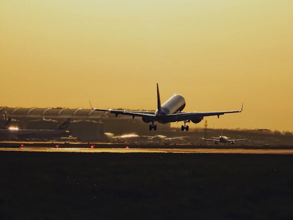 A sleek cargo plane taking off against a vibrant orange sunset, symbolizing speed and reliability.
