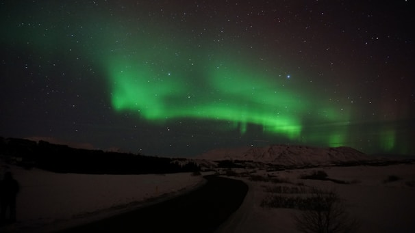 A serene Icelandic landscape illuminated by vibrant northern lights under a starry sky.