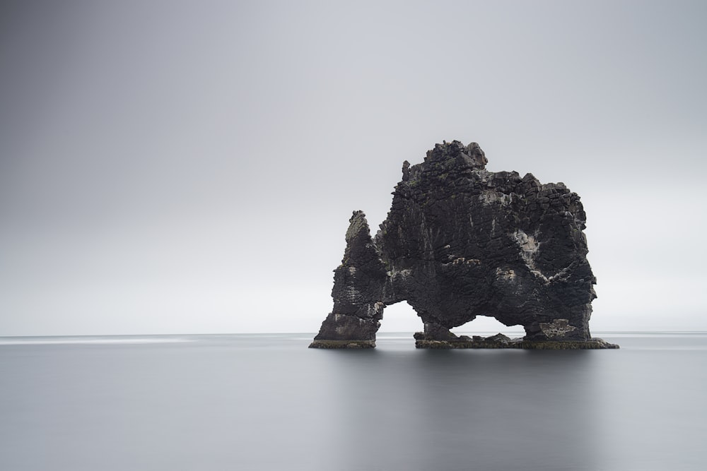 black rock formation on body of water