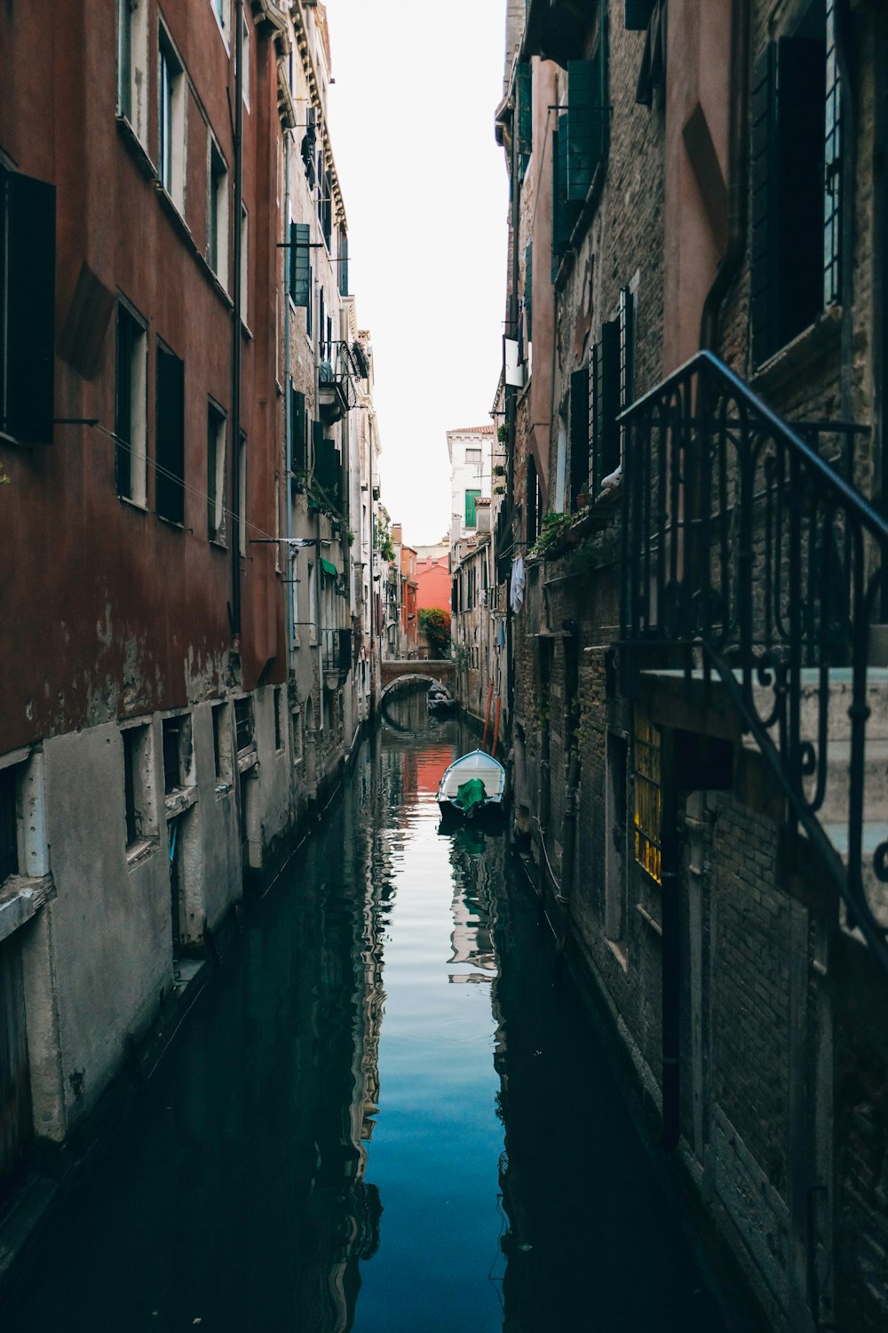 white boat on canal in between concrete houses