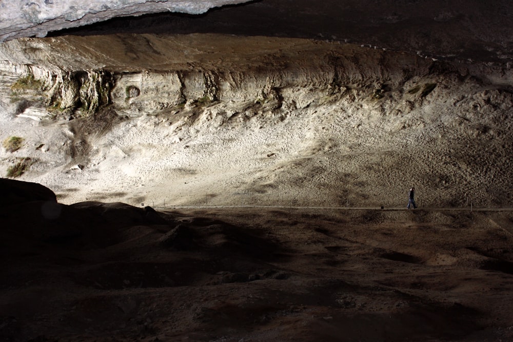 person walking inside cave with sun lights