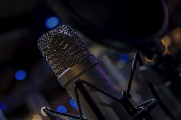 Close-up of a microphone with colorful pop culture posters blurred in the background.