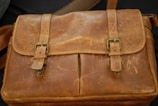 A sturdy leather satchel hanging from a weathered belt on a mannequin.