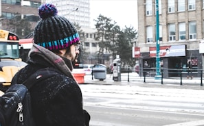 Outdoor scene of a person wearing a grey knitted hat on a chilly morning commute through city streets