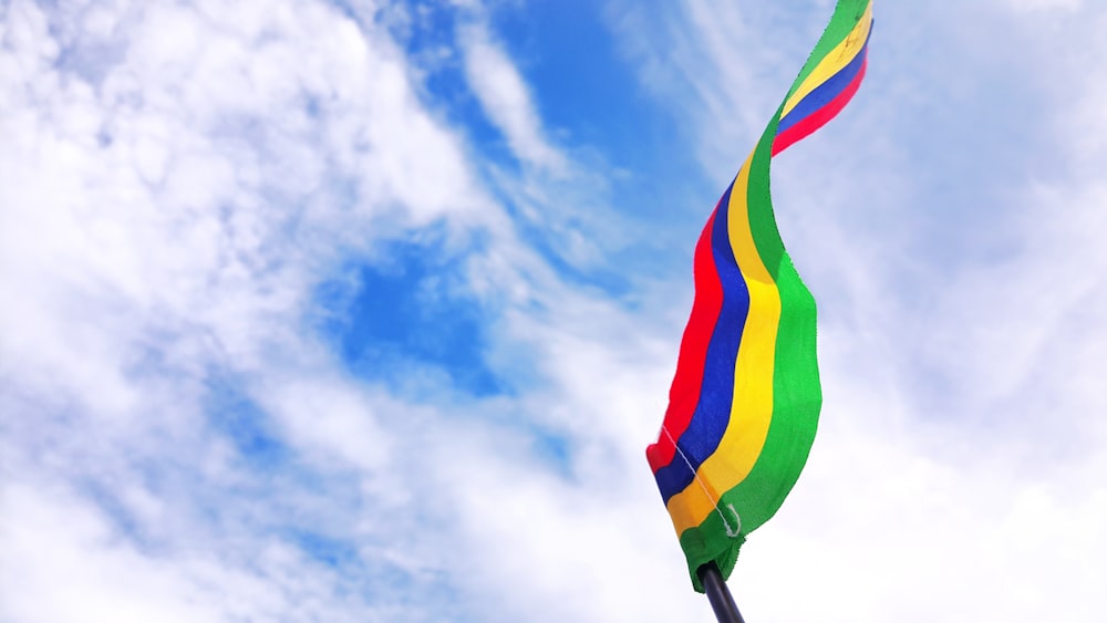 bandera a rayas rojas, azules, amarillas y verdes bajo el cielo azul