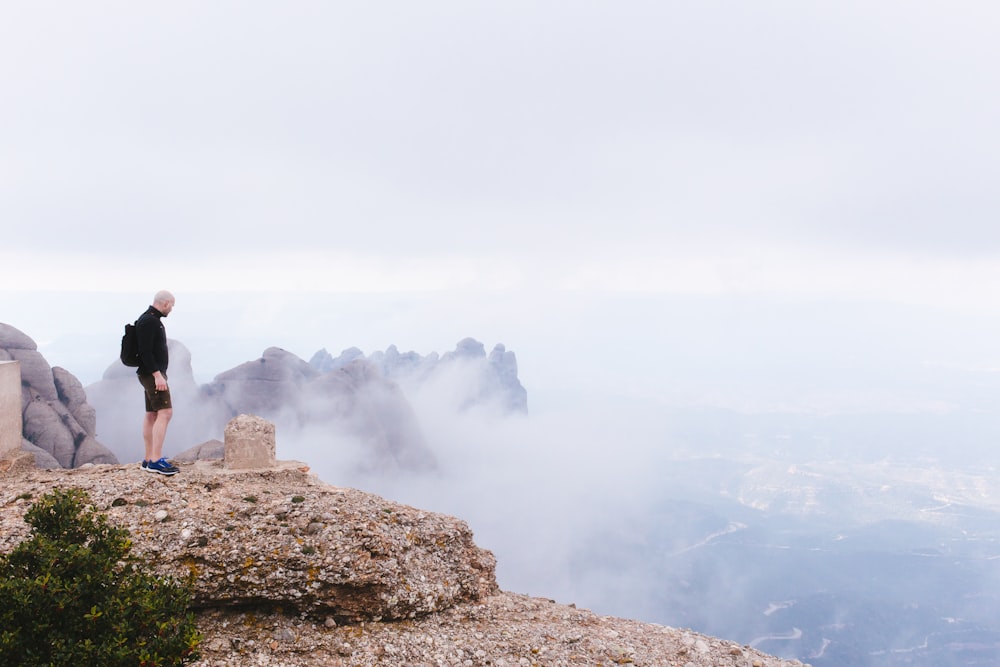 man standing white facing cliff