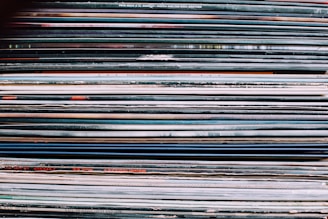 A colorful stack of vinyl record covers fanned out on a wooden table