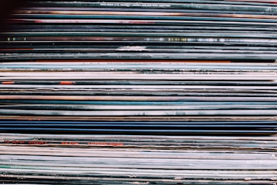 Stack of colorful vinyl album covers leaning against each other on a wooden shelf