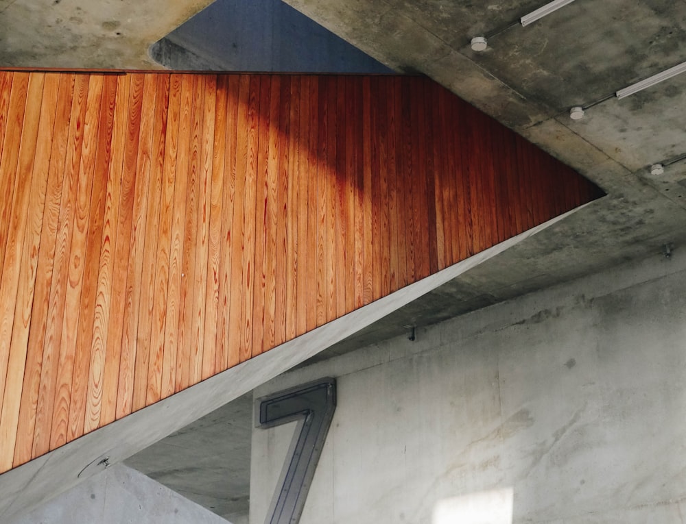 Wooden panelling on the side of a staircase in a building with bare concrete walls