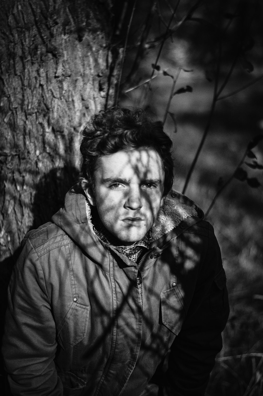 grayscale photo of man under tree