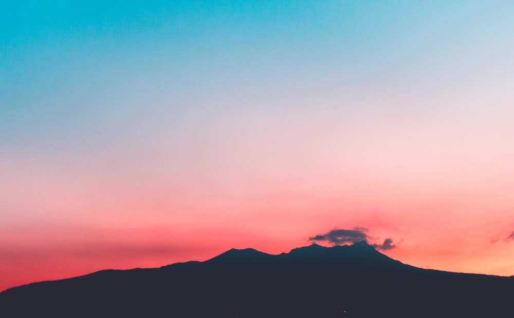 silhouette de montagne sous ciel rose et bleu