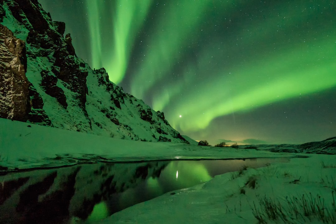 snow covered mountain with aurora borealis, Green stripes behind the rock