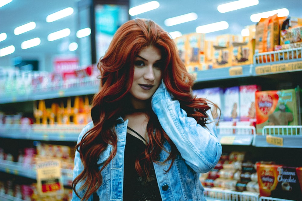 Mujer en chaqueta de mezclilla azul sosteniendo su cara en una tienda conveniente