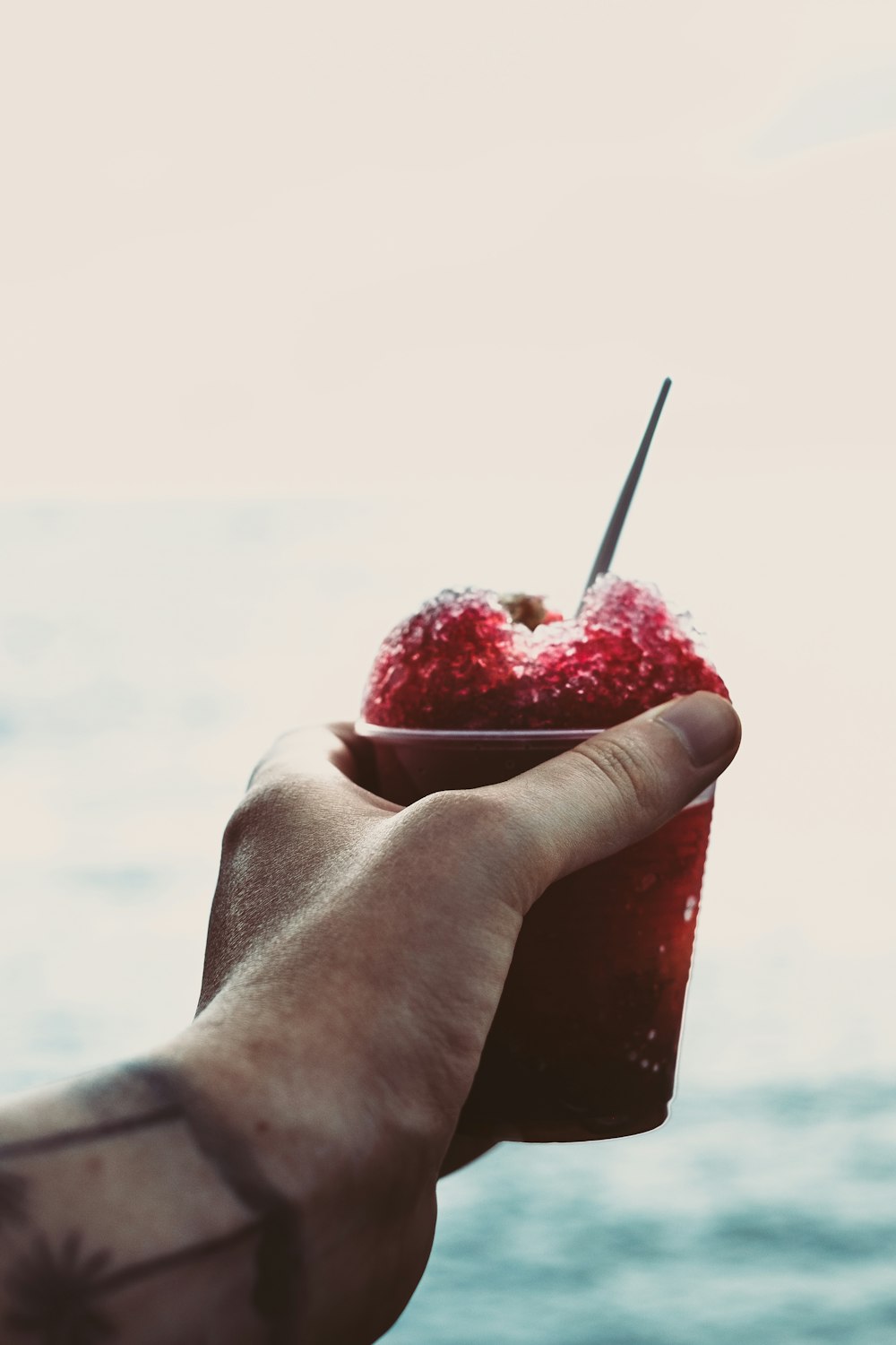 person holding red dessert in cup