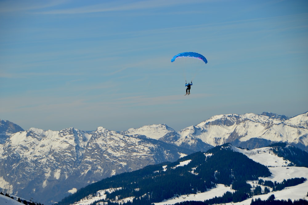 person parachuting above snow covered mountains